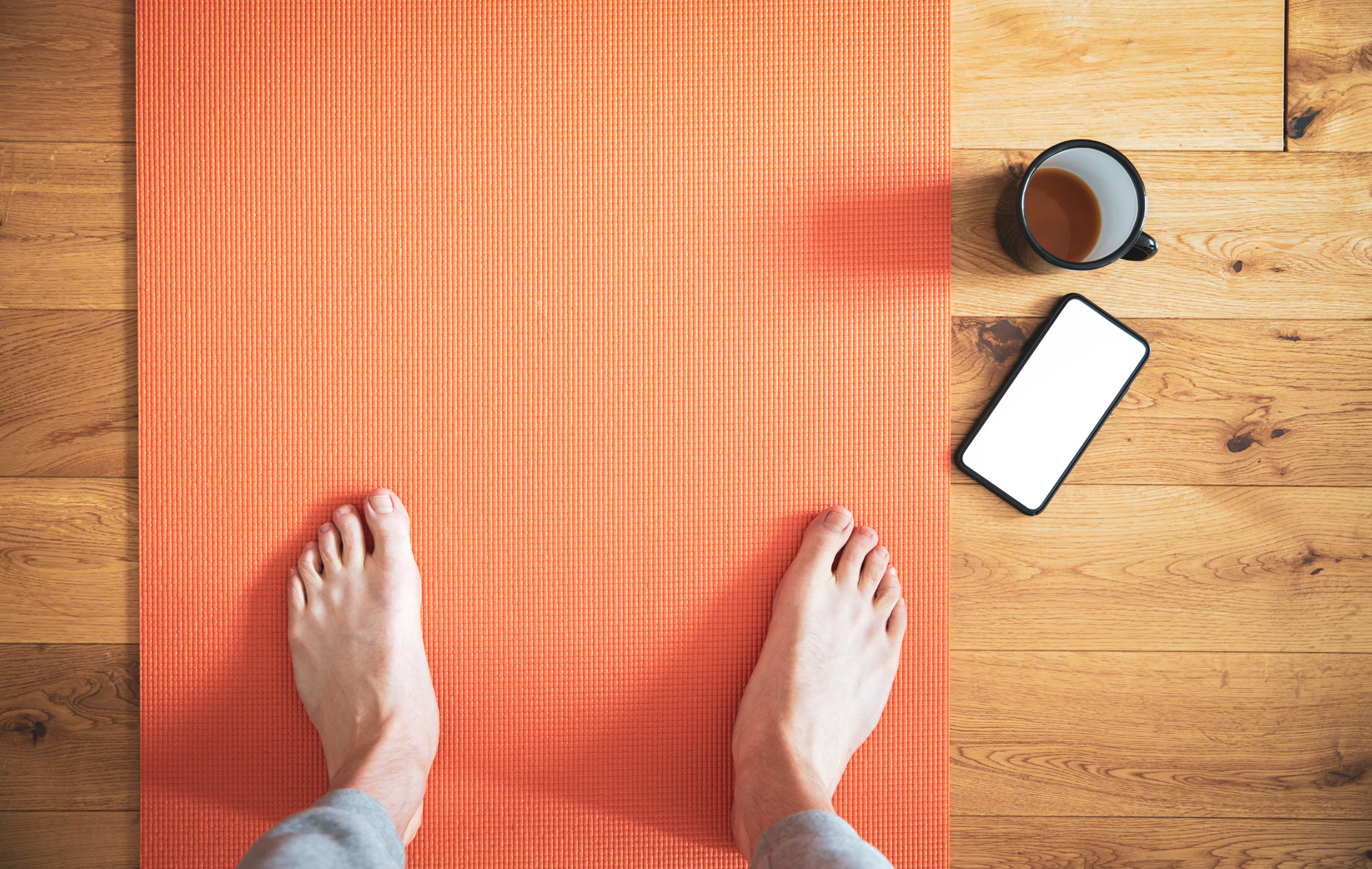 Man Standing on Yoga Mat with Coffee and Smartphone